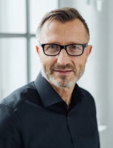 Aufnahme eines Mannes mit Brille, der in die Kamera schaut