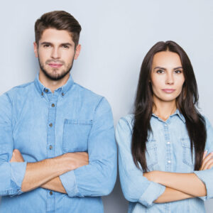 Mann und Frau stehen Schulter an Schulter mit verschränkten Armen nebeneinander